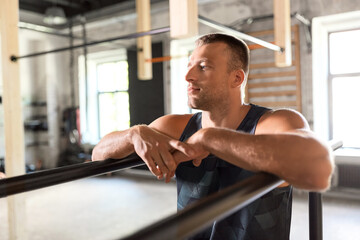 fitness, sport, training and lifestyle concept - young man exercising on parallel bars in gym