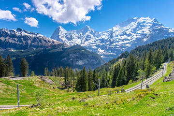 The railroad track to Murren an alpine village in Switzerland and the snow capped mountains beyond