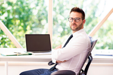 Cropped shot of businessman looking at camera and smiling while sitting at office desk