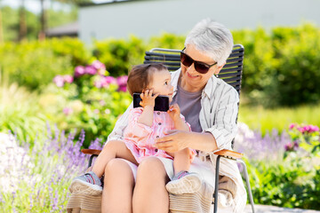 family, generation and people concept - happy grandmother with baby granddaughter calling on...