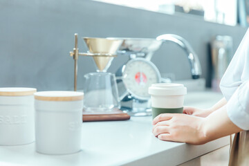 朝の明るい白いキッチンでドリップコーヒーを手に持っている　coffee drip kitchen