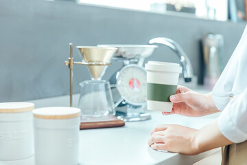 朝の明るい白いキッチンでドリップコーヒーを手に持っている　coffee drip kitchen