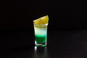 Layered shot on black background. Alcohol cocktail with syrup, liquor and tequila .