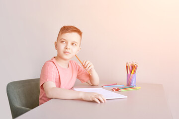 Little boy drawing. Closed Locking Exercise. Homemade routine. School lessons. Write pencil on piece of paper. Home study. Elementary preschool. Male kid student. Thinking or dreaming