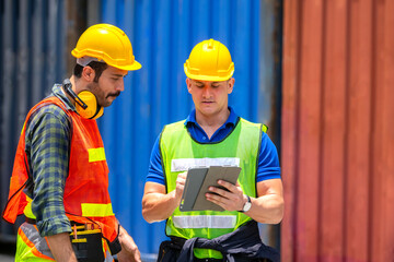 Industrial worker working at cargo freight logistic warehouse wit computer tablet for online assignment. Import and export business.