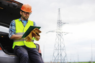 A man in a helmet and uniform, an electrician in the field. Professional electrician engineer...