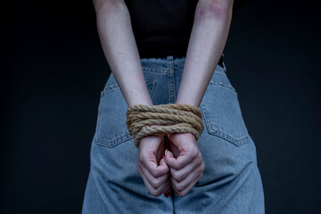 Young girl with bound hands on black background, close up