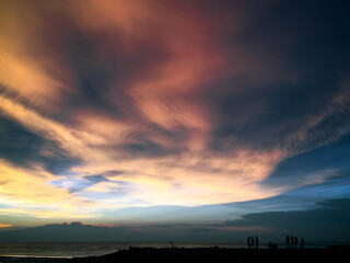 Beautiful beach sunset and many figures in the distance with amazing sky 