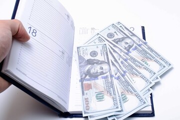 100 dollar bills lie in a blue notebook on a white background in close-up. A man's hand opens a notebook with dollars. Find, a stock for a rainy day dollars. Inheritance