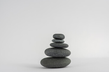 Obraz na płótnie Canvas One simplicity stones cairn isolated on white background, group of five black pebbles in tower