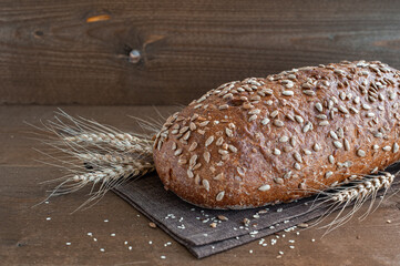 Fresh bread sprinkled with sesame seeds on a dark background with coals and linen napkin. View from above. Copy space.