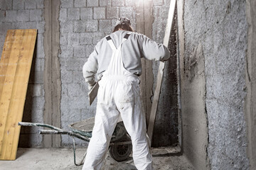 Real construction worker making a wall inside the new house.