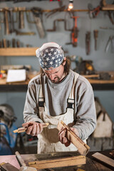 Male carpenter working on old wood in a retro vintage workshop.