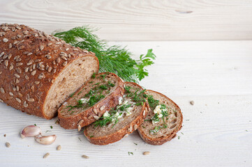 Pieces of whole grain bread with butter, dill, salt and garlic on a white wooden background. Copy space.