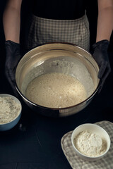 Woman in checkered apron hold bowl with liquid yeast dough. Process of making bakery. Adjarian Khachapuri Recipe – Georgian cheese bread.