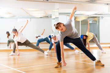 Fototapeta na wymiar Positive teenage girls and boys training hip hop in dance studio, dance classes for teens
