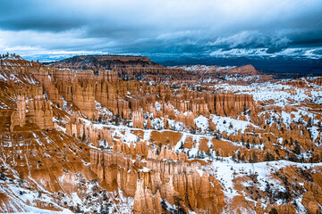Beautiful view in Bryce Canyon National park in Utah. Orange rocks clouded with white snow makes...