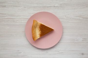 Homemade Sugar Cream Pie on a pink plate on a white wooden surface, top view. Flat lay, overhead, from above.