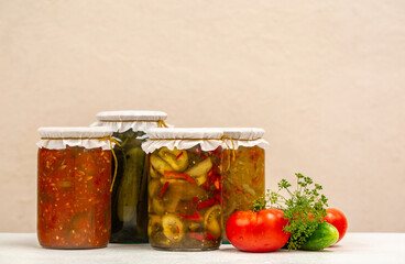 Variety of Jars with preserved vegetables and vegetable salads on beige background. Copy space.