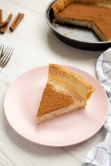 Homemade Sugar Cream Pie on a pink plate on a white wooden surface, low angle view. Close-up.