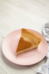 Slice of Homemade Sugar Cream Pie on a pink plate on a white wooden table, low angle view. Copy space.