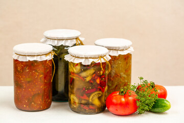 Variety of Jars with preserved vegetables and vegetable salads on beige background. 