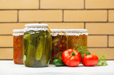 Variety of Jars with preserved vegetables and vegetable salads on brickwork background. 