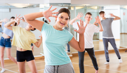 Portrait of emotional teenager girl doing dance workout during group class in studio