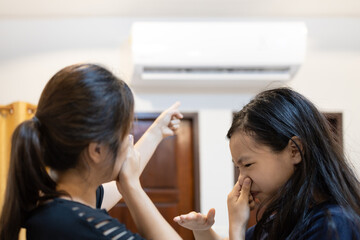 Asian woman and child girl are closing her nose, bad smell,musty smell of air conditioner has a problems,dust and dirt coming in through the air ventilation,concept for cleaning check air conditioner - obrazy, fototapety, plakaty
