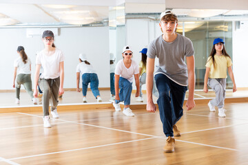 Fototapeta na wymiar Group of teenagers in casual clothes training hip-hop in class, learning modern dance movements