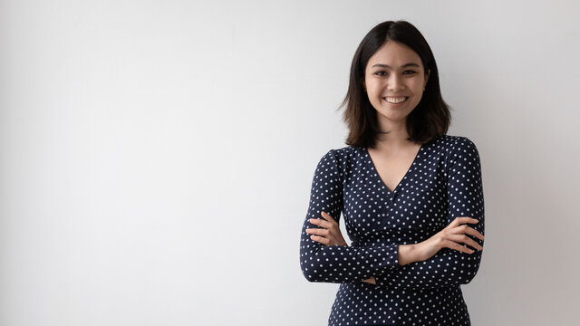Portrait of happy young Asian woman stand pose isolated on grey studio background show leadership and confidence, smiling confident Vietnamese female arms crossed look at camera, employment concept
