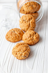 Homemade oatmeal cookies on white wooden table with milk on background