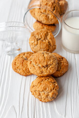 Homemade oatmeal cookies on white wooden table with milk on background