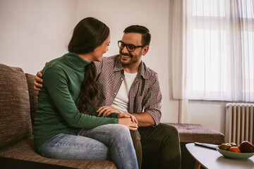 Happy couple is relaxing and talking at home.