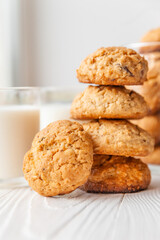 Homemade oatmeal cookies on white wooden table with milk on background