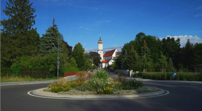 Bahnhofstra&szlig;e in Aichach, mit reich bepflanzter Kreisverkehr-Mittelinsel und der Pfarrkirche
