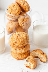 Homemade oatmeal cookies on white wooden table with milk on background