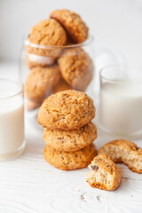 Homemade oatmeal cookies on white wooden table with milk on background