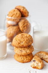 Homemade oatmeal cookies on white wooden table with milk on background