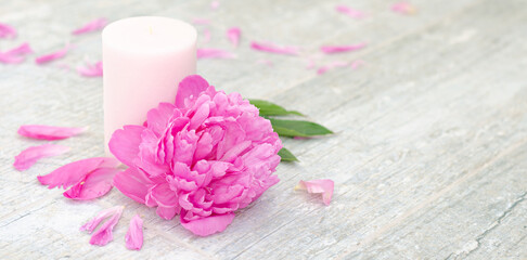 Obraz na płótnie Canvas Beautiful pink peony flowers and white candle on light grey stone background with copy space for your text top view. Greeting card, SPA and romantic concept. Banner.