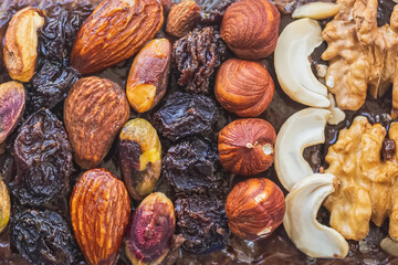 Homemade chocolate cake with hazelnuts, cashews, walnuts, prunes and almonds close-up. Top view, flat lay food texture background
