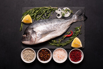 raw dorado fish on black board with seasonings and spices