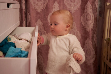 baby pulls clothes out of the drawer
