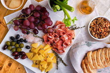 Overhead view of set of various appetizers for wine - cheese, prosciutto, grape, olives, walnuts and celery