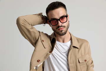 sexy young man in jacket holding hand behind neck