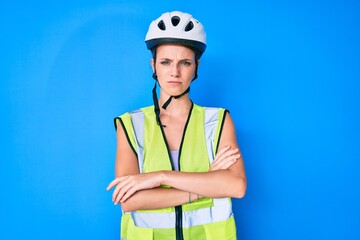 Young caucasian girl wearing bike helmet and reflective vest skeptic and nervous, disapproving expression on face with crossed arms. negative person.