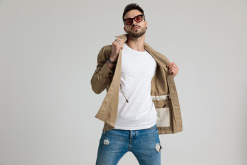 cool unshaved young guy adjusting jacket and posing