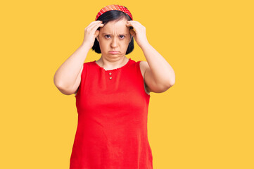 Brunette woman with down syndrome wearing casual clothes suffering from headache desperate and stressed because pain and migraine. hands on head.