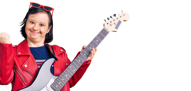 Brunette woman with down syndrome playing electric guitar screaming proud, celebrating victory and success very excited with raised arms