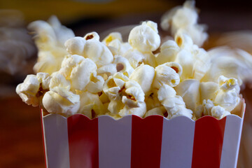 Popcorn flying out of cardboard box. red and white striped popcorn bucket with flying popcorn in...
